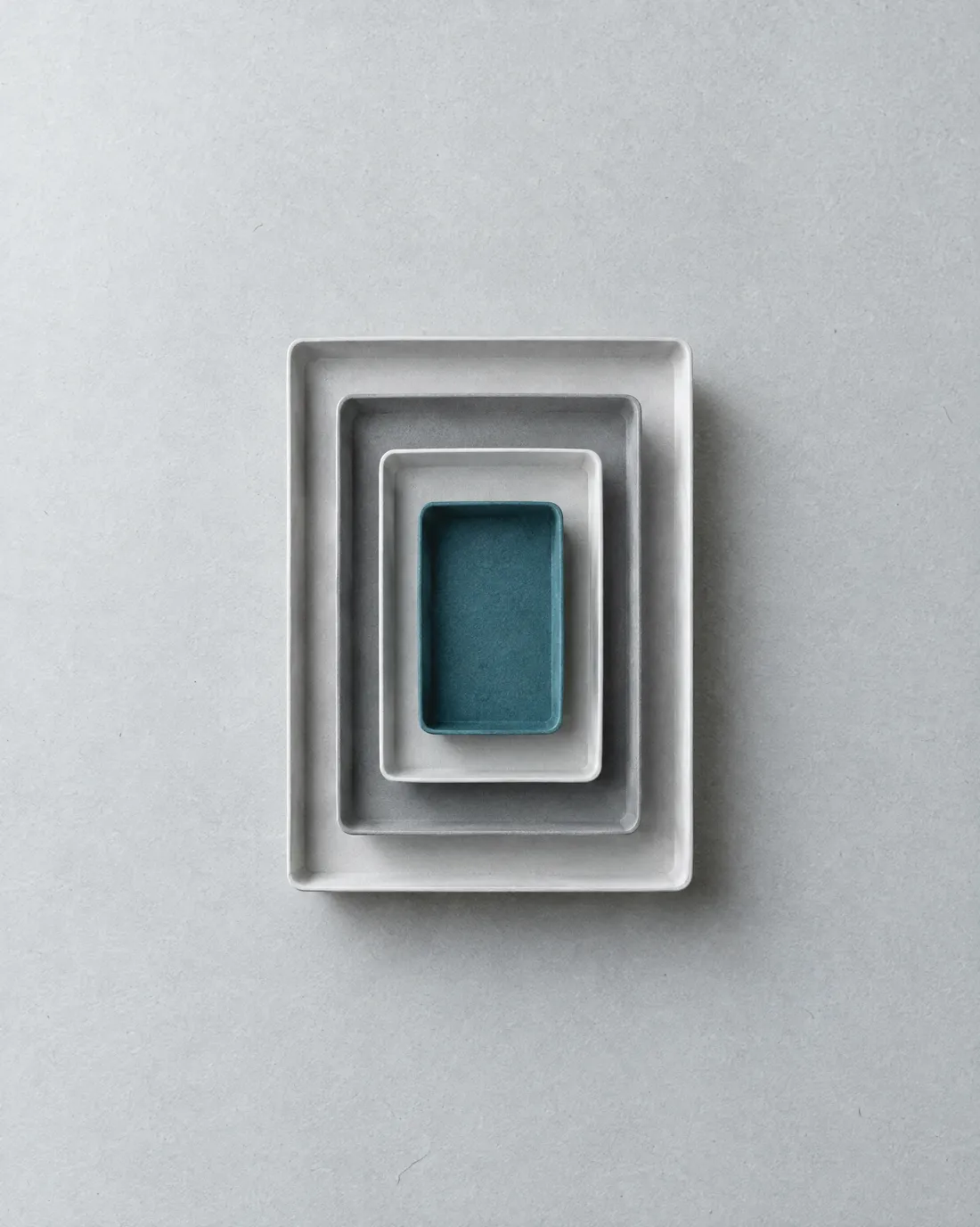 Nested white and grey desk trays stacked in orderly tiers, one tray blue.